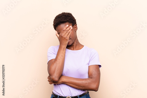 young pretty black womanlooking stressed, ashamed or upset, with a headache, covering face with hand photo