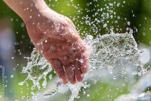 Hand of a man in the spray of water of the fountain