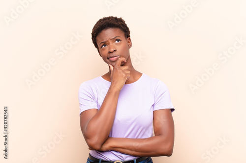 young pretty black womanthinking, feeling doubtful and confused, with different options, wondering which decision to make photo