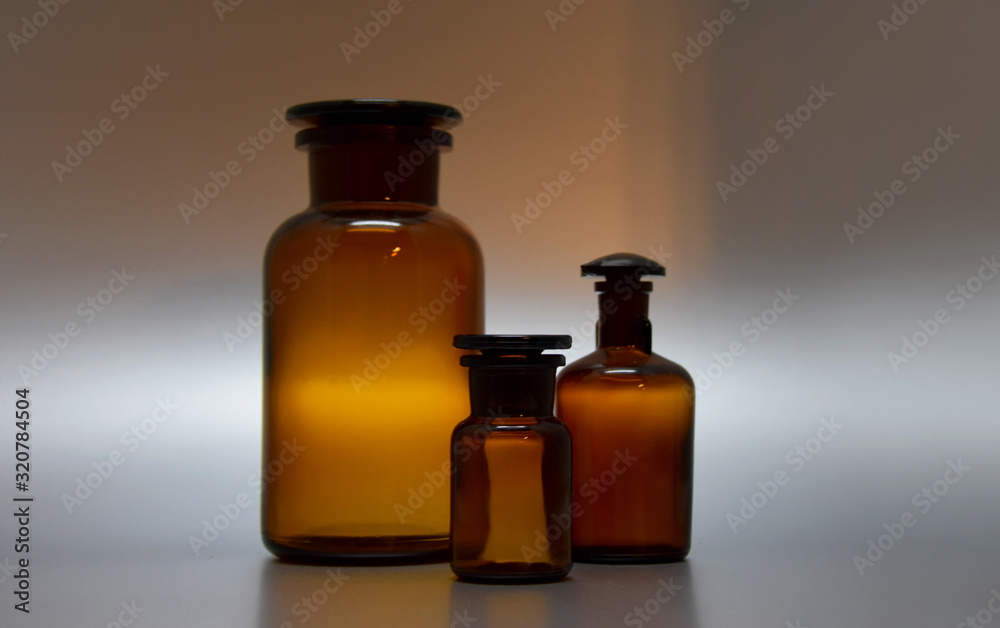 Brown laboratory glassware stock images. Three brown vials stock images. Empty cosmetic bottle. Brown glass containers. Brown chemical glass. Laboratory vial on a silver background