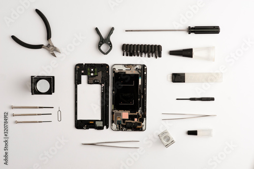 set of objects mobile repair on white background, mobile workshop concept, various tools, broken phone, magnifying glass, glue, screwdrivers, top view on white background photo