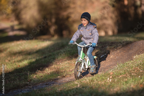 Six years old boy rides bicycle from the hill in the park.