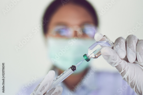 Syringe medication injection and needle in hand nurse for giving patient vaccine prophylactic - Medication drug bottle equipment medical liquid drug , African american female doctor