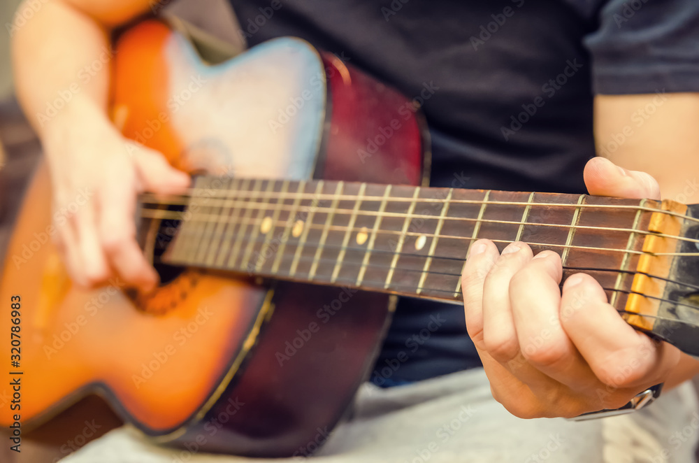 man plays a brown guitar in close-up