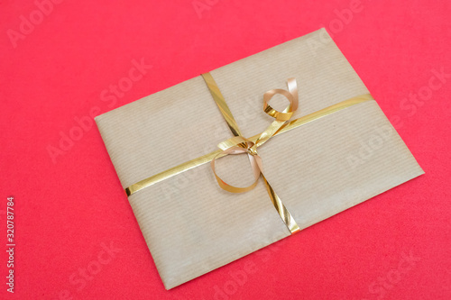 Craft gift packaging with a gold ribbon on a red background
