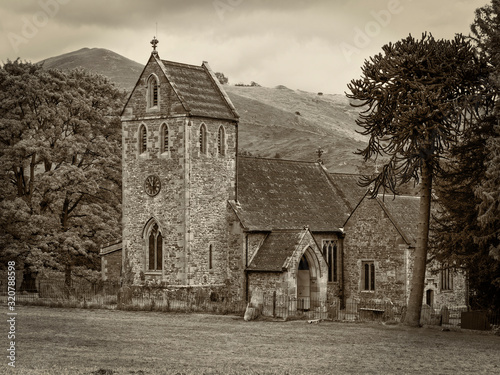 Close up of Ilam church with the hills of Derbyshie in the background - sepia toned image photo