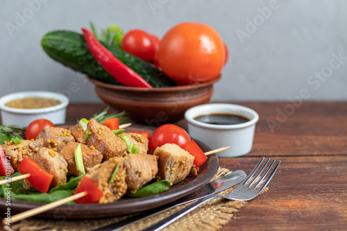 Chicken breast skewers with bell pepper. The meat is marinated in soy sauce with honey and mustard. Decorated with sprigs of rosemary. In the background are soy and vegetables for the salad.