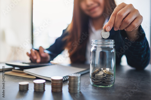 Closeup image of a businesswoman stacking and putting coins in a glass jar © Farknot Architect