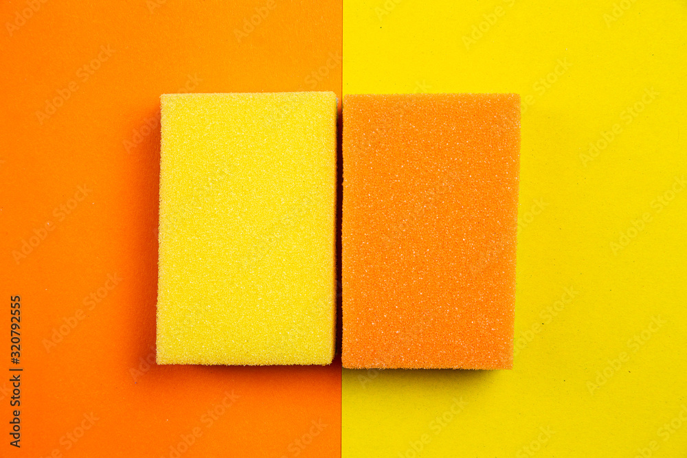 Yellow and orange sponges for washing dishes on a colored background Yellow and orange sponges for washing dishes on a colored background