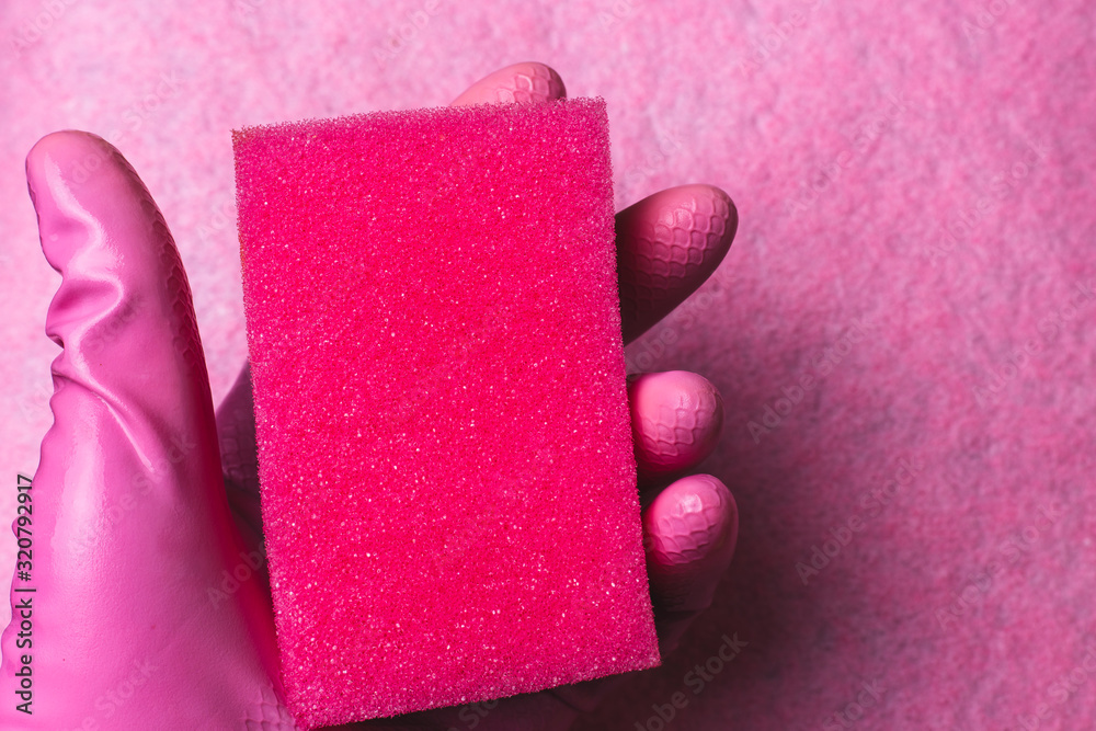 Hand in rubber glove holds sponge on pink background Hand in rubber glove holds sponge on pink background