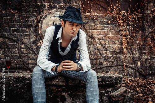 Mid adult fedora styled man relaxing outdoors. © LumineImages