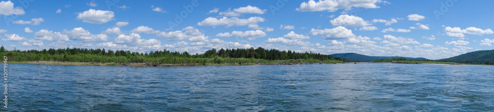 Summer panorama of the river. Snow-white clouds on a background of blue sky. Kitoy River Russia