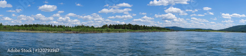 Summer panorama of the river. Snow-white clouds on a background of blue sky. Kitoy River Russia