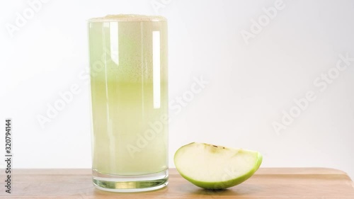 Hand picking up green apple juice in a glass