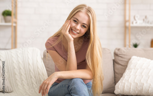 Portrait of attractive girl sitting on couch and smiling