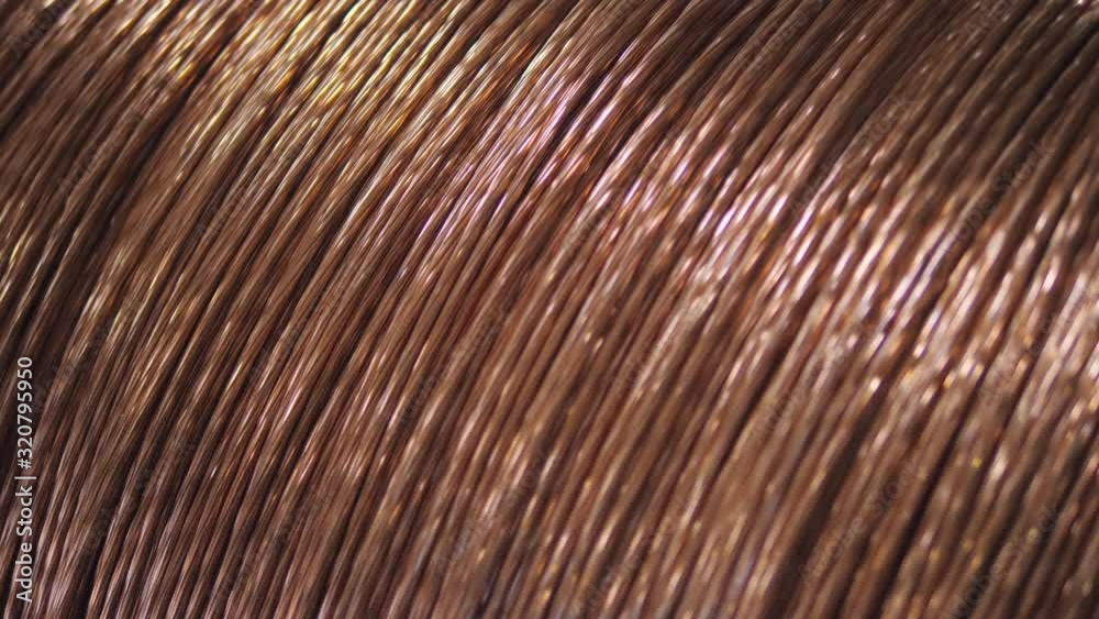 Close-up copper wire is wound on the large coil at the factory for the manufacture of electric cable.