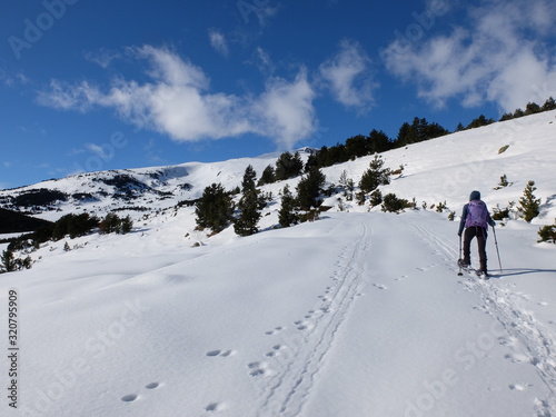 Jeune femme randonneuse en raquette dans la neige en montagne sous le soleil des Pyrénées Orientales de Cerdagne