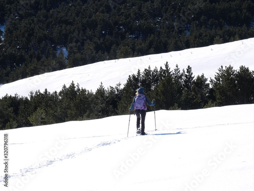 Jeune femme randonneuse en raquette dans la neige en montagne sous le soleil des Pyrénées Orientales de Cerdagne