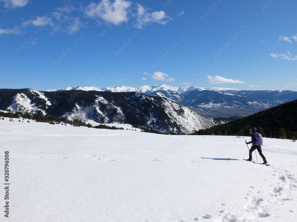 Jeune femme randonneuse en raquette dans la neige en montagne sous le soleil des Pyrénées Orientales de Cerdagne