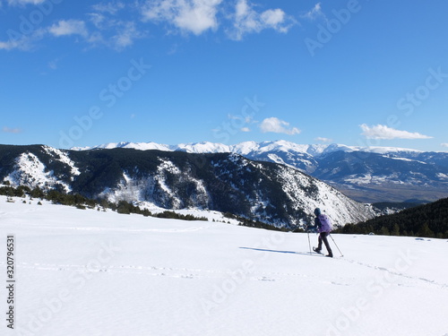 Jeune femme randonneuse en raquette dans la neige en montagne sous le soleil des Pyrénées Orientales de Cerdagne