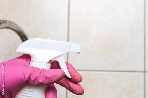 Woman Hand in pink glove cleans with spray tile wall