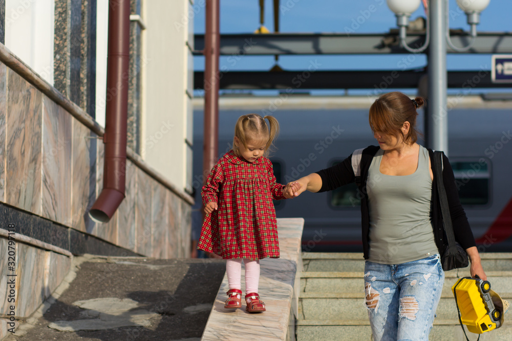 Caucasian child of two years old walking down holding the mother hand supporting woman