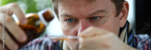 Sick man holding in hands vial with syrup portrait photo