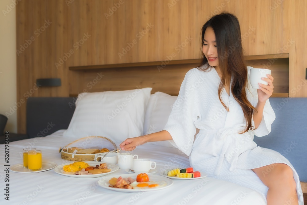 Portrait beautiful young asian woman happy enjoy with breakfast on bed in bedroom