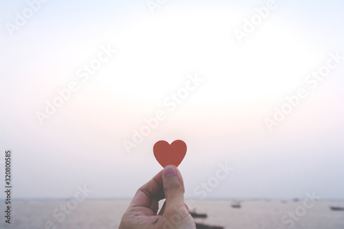 Close up of hand man holding a paper heart with the sea background. love concept  happy valentine.