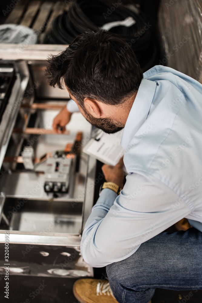 Middle age businessman doing quality control checking at industry production. Factory for industrial production of electric housings and surge arresters. Middle age businessman doing quality control checking at industry production. Factory for industrial production of electric housings and surge arresters.