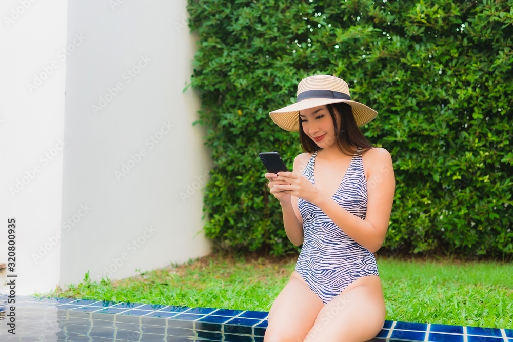 Portrait young asian woman using smart mobile phone around outdoor swimming pool
