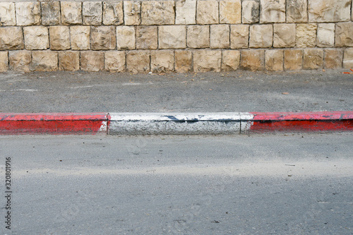 Photos Red and white colored road curbstone indicating the prohibition of Parking on Is