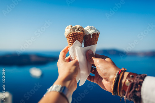 Ice-cream in cones. Couple eating ice-cream holding it on sea background. Sweet tasty summer food. Close up