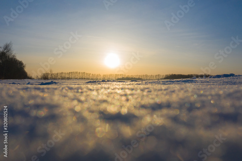Winter frosty day. The time of sunset. Bokeh snowflakes sparkle in the sun