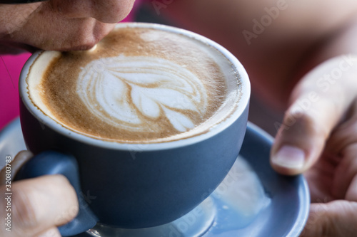 Closeup of woman enjoying sipping coffee latte with art
