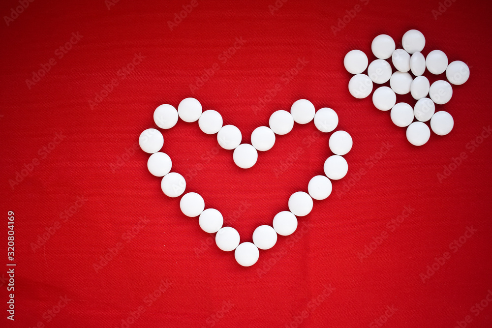 heart made of pills on red background