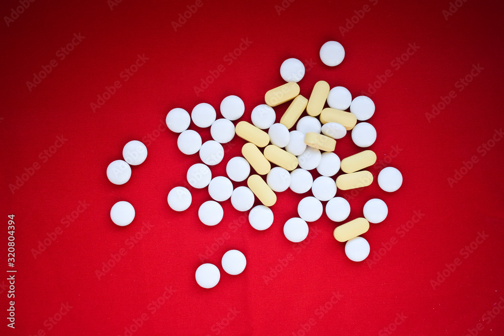 white and yellow pills on a red background white and yellow pills on a red background