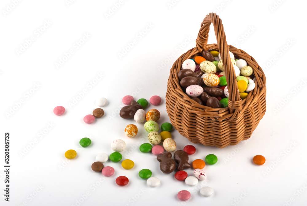 Easter basket with colored candies on a white background with a copy of the space Easter basket with colored candies on a white background with a copy of the space