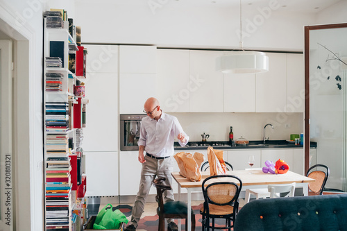 Mid adult man indoor at home unpacking groceries in the kitchen photo