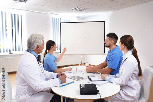 Team of doctors using video projector during conference indoors