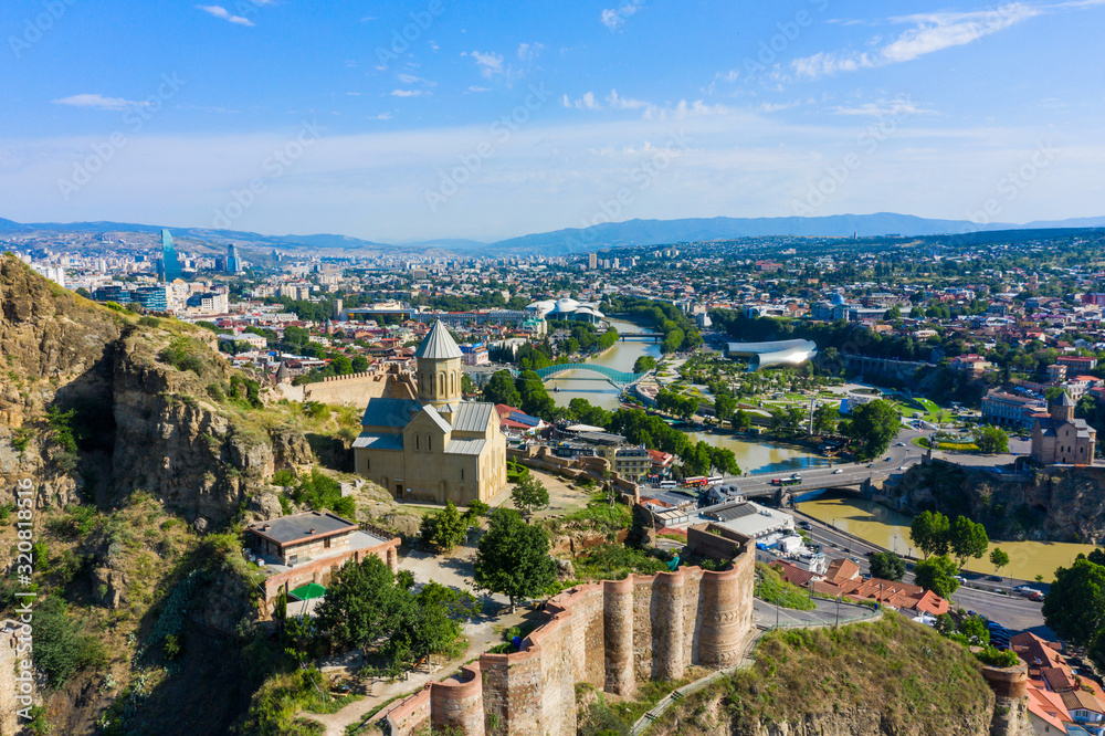 Fototapeta premium Panorama of the old town on Sololaki hill, crowned with Narikala fortress, the Kura river and cars traffic with blure in Tbilisi, Georgia.