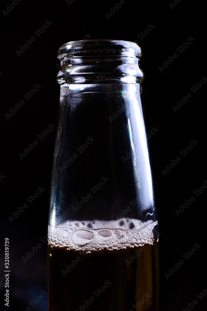Beer foam in a bottle on a dark background.