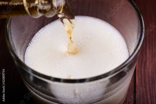 Pouring beer with foam into a glass.