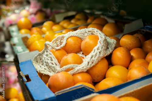 a mesh eco bag with fresh fruits lay on top of crate with food in local farmer grocery store