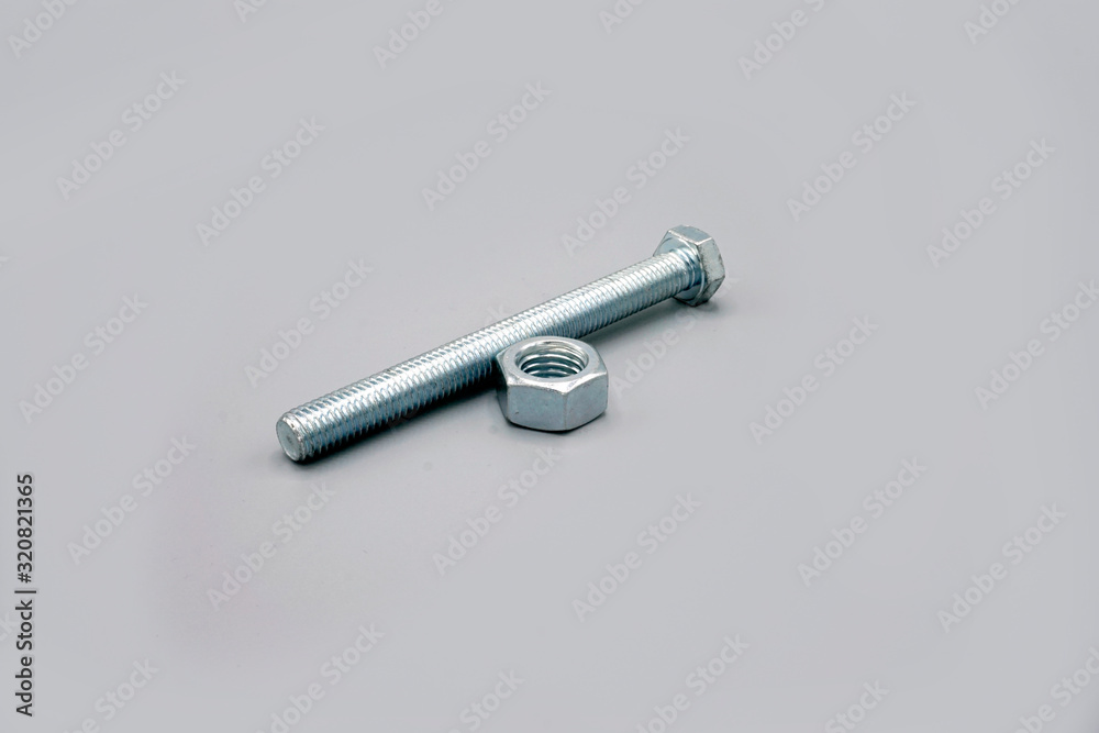Metal screws and nuts isolated on gray background. New and shiny chrome screws and nuts. Copy space. Metal screws and nuts isolated on gray background. New and shiny chrome screws and nuts. Copy space.