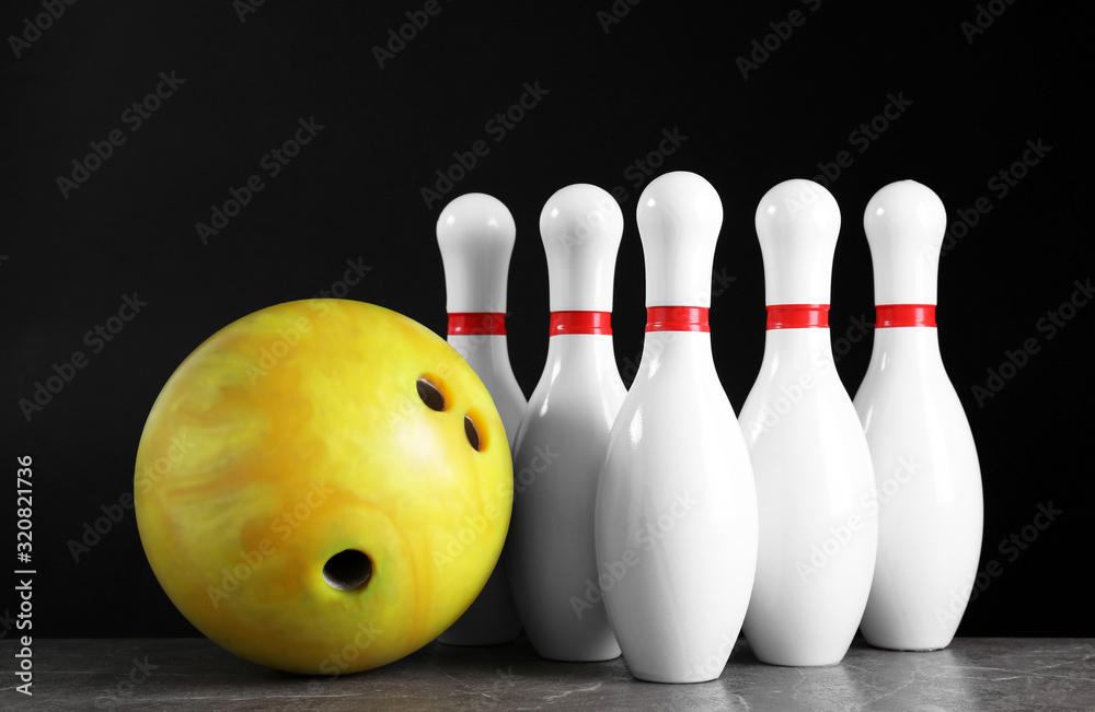 Yellow bowling ball and pins on grey stone table Yellow bowling ball and pins on grey stone table