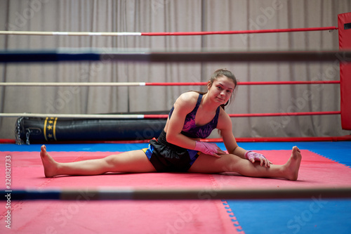 Female kickboxer stretching in the ring