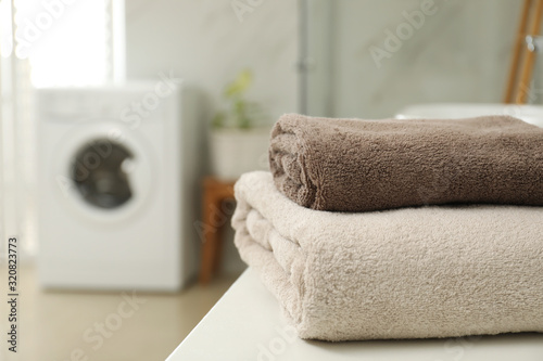 Stack of clean towels on table in laundry room. Space for text