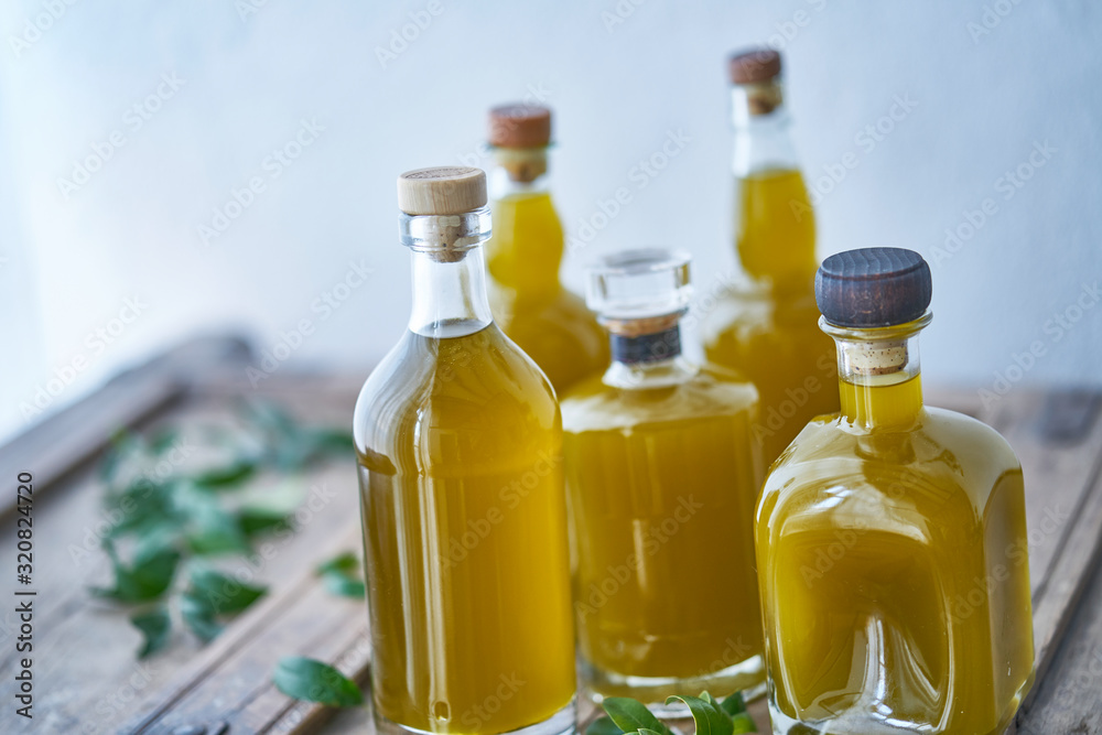 Closeup of glass bottles filled with golden liquid juice or oil. Health cooking in mediterranean kitchen good for wellness and body relaxed summer feeling Closeup of glass bottles filled with golden liquid juice or oil. Health cooking in mediterranean kitchen good for wellness and body relaxed summer feeling