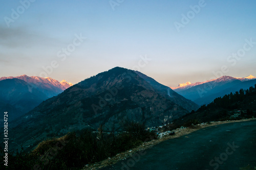 Last sunlight on mountains seen from small village in Uttarakhand, India. Winter trek to Kedarkantha Peak on Christmas and new year.